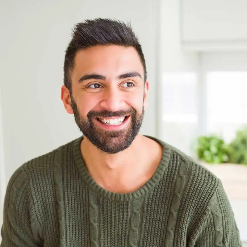 A bearded man smiling in a green shirt.