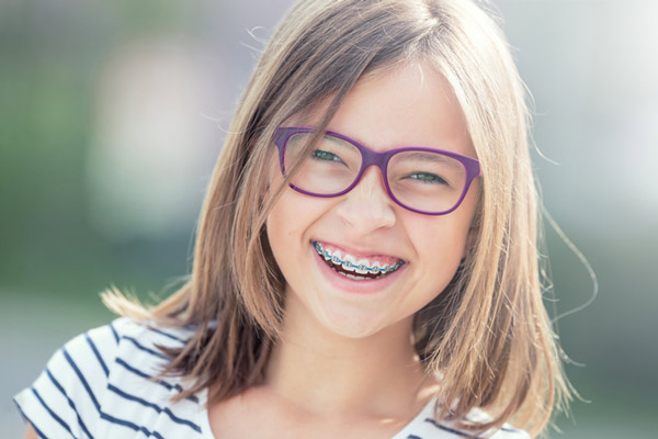 Young girl with glasses on smiling with braces